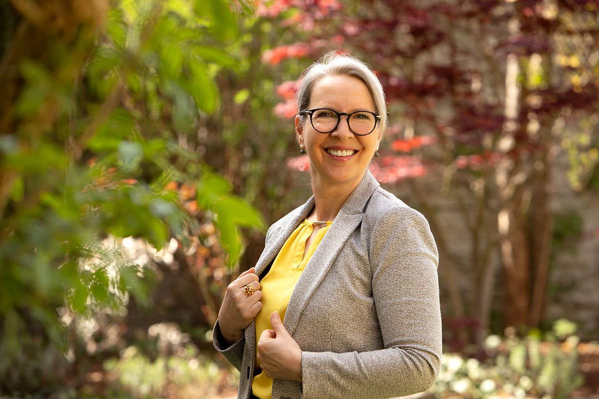 Birgit Strasser-Jentsch lächelt im Garten vor rotem Laub